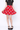 Person wearing a red skirt with a pattern and black top on a white background