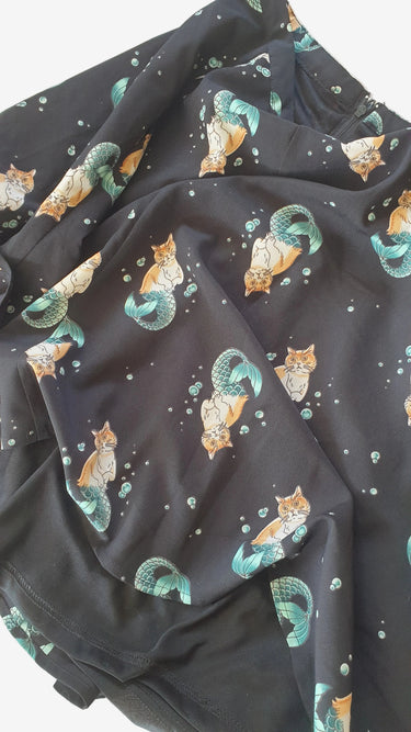 Dark fabric with cat and moon pattern on a wooden surface
