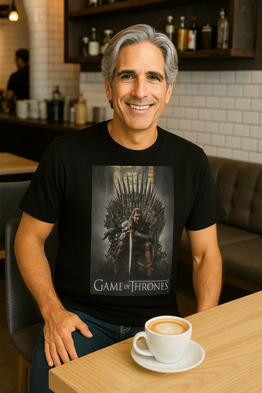 Man wearing a 'Game of Thrones' t-shirt sitting at a table with a coffee cup.