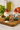 Two gnome-shaped salt and pepper shakers on a wooden board with a kitchen background.