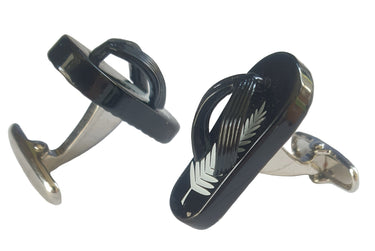 Black and silver cufflinks with a leaf design on a white surface
