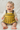 Baby wearing a yellow knitted dress with gray accents on a white background