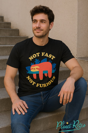 Man wearing a black t-shirt with a colourful sloth graphic and text, sitting on steps.
