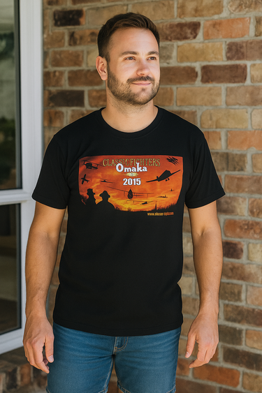 Man wearing a black t-shirt with a graphic design in front of a brick wall.