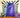 Purple Dalek figure in front of a black and white striped pillow with a candle and flowers on a wooden surface.  Planet Retro NZ.