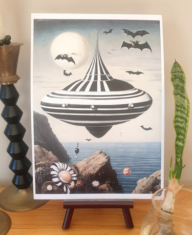 Framed artwork of a UFO over a coastal landscape with bats and a moon.  Planet Retro NZ