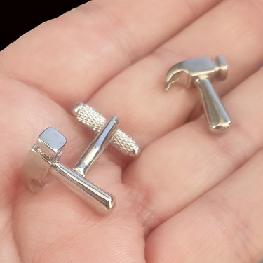 Silver hammer-shaped cufflinks on a hand