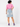 Back view of model wearing Planet Retro Stranger Things Vecna upcycled light-wash denim skirt, pink shirt and purple high-top trainers – AI styled image