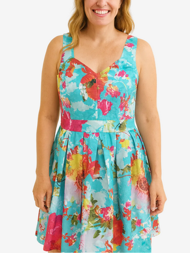 Woman wearing a colorful floral dress against a plain background