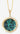 Gold necklace with a round pendant featuring green paua shell on a gray background