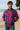 Man wearing a pink and blue checkered jacket on a beach