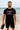 Man wearing a black t-shirt with 'Waikanae Football' text on a beach