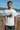Man wearing a white t-shirt with a graphic design on a beach.  Planet Retro NZ.