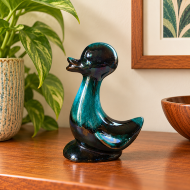 Vintage Blue Mountain Pottery green duckling figurine, 14cm tall, displayed on a wooden cabinet against a cream wall