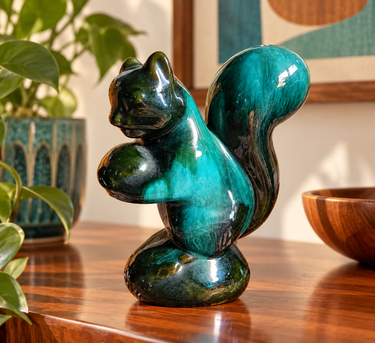 Vintage Blue Mountain Pottery squirrel figurine with teal and green drip glaze displayed on a mid-century wooden sideboard