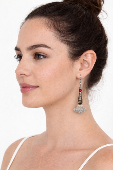 Woman wearing a silver earring with a red gemstone on a white background
