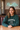 Woman wearing a green 'Champion' sweatshirt sitting at a table with 'Planet Retro' sign in the background