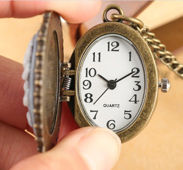 Vintage-style pocket watch held by a hand with a blurred background