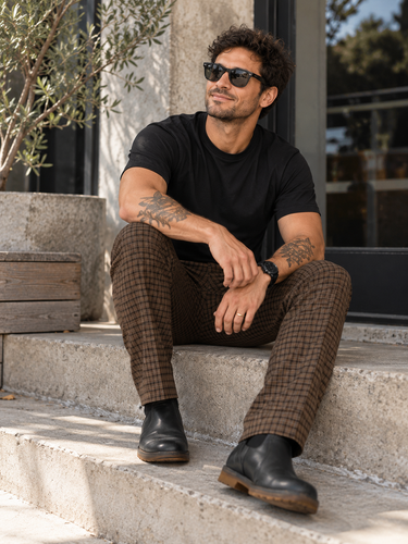 I Love Ugly brown checked men's pants size Large styled outdoors on seated male model wearing black sunglasses