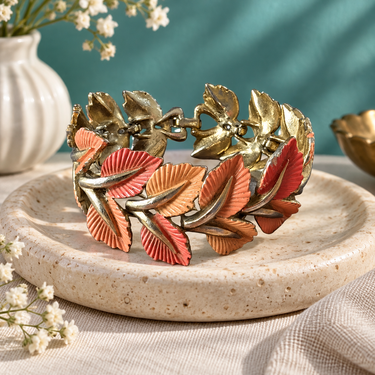 Vintage Jewelcraft coral and peach enamel leaf bracelet styled on a ceramic tray