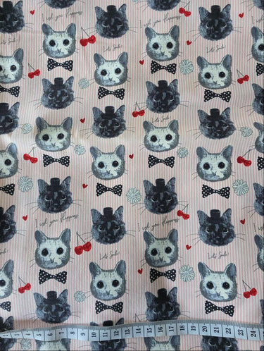 Overall view of KOKKA cat faces and bows on pale pink pinstripe cotton fabric