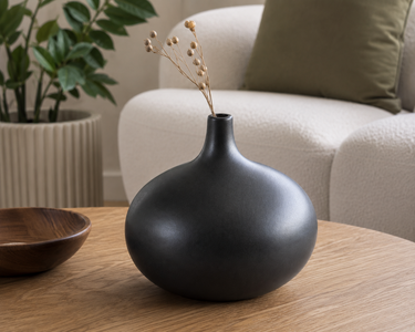 Matte black sculptural ceramic vase with rounded body and narrow neck.
