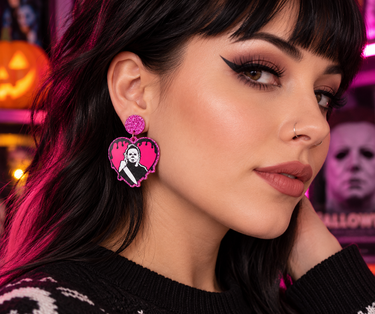 Model wearing pink glitter Michael Myers Halloween heart earrings in a horror-inspired setting