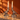 Pair of Nel Lusso smoky glass bird candle holders with lit ivory taper candles against a burnt orange wall