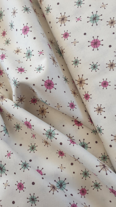 Close-up of Northcott Mel’s Dinner pink and mint atomic stars cotton print