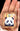 Small brooch of a gold-framed picture of a panda with a colorful background held in a hand.