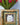 Decorative gold frame with a picture of a cat, placed on a surface with a bouquet of flowers in the background.