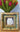 Decorative gold frame with a picture of a cat, placed on a surface with a bouquet of flowers in the background.