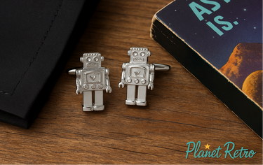 Robot-shaped cufflinks on a wooden surface with 'Planet Retro' branding.