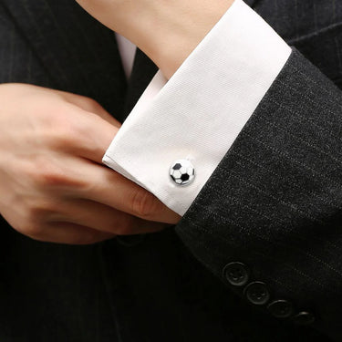 Close-up of a person wearing a black suit with white cufflinks.