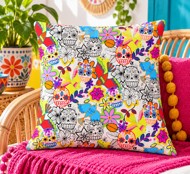 Colourful Sugar Skulls & Birds handmade cushion cover styled on wicker chair with bright pink throw and plants