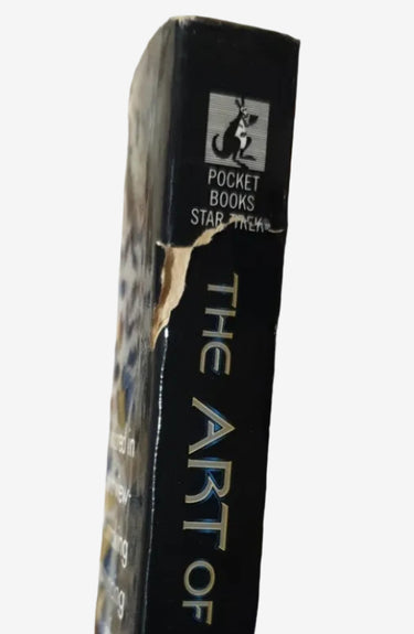 A close-up of a book titled 'The Art of Star Trek' showing its black spine with gold lettering.