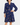 Female model wearing Trollied Dolly navy blue swallows print retro dress with pussy bow neckline and navy kitten heels, front view