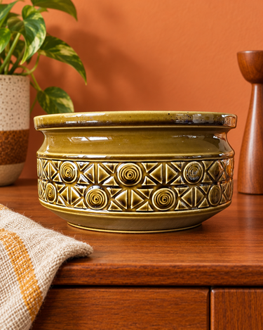 Vintage Beswick Zorba olive-green ceramic large bowl styled against a pale burnt orange wall on a wooden sideboard