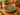 Five vintage Beswick Zorba olive-green plates stacked on a teak dining table in a retro interior