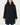 A woman modeling a black hooded coat with a fuzzy dark hood, paired with blue jeans and black ankle boots, against a plain light gray studio background.