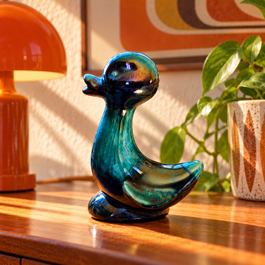 Vintage Blue Mountain Pottery green duck figurine styled with a retro orange lamp and timber furniture