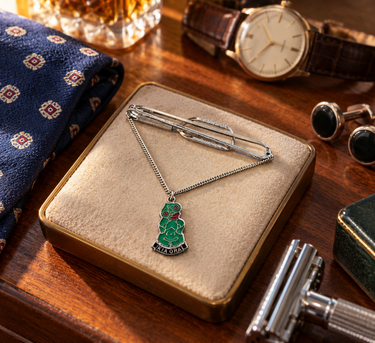 Vintage Kia Ora tiki charm tie bar on a cream jewellery tray with retro gentleman's accessories