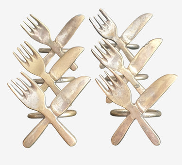 Vintage 1970s brass napkin ring with crossed knife and fork design.