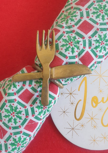 Vintage 1970s brass napkin ring with crossed knife and fork design.