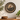 A round hand-painted wooden wall plaque featuring a magpie bird, displayed on a light beige wall above a wooden console table with decorative plants and a bowl.