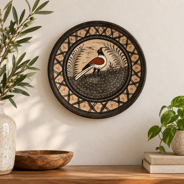 A round hand-painted wooden wall plaque featuring a magpie bird, displayed on a light beige wall above a wooden console table with decorative plants and a bowl.