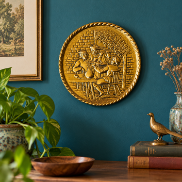 Vintage Peerage brass musicians wall plate displayed on a teal blue wall in a styled vintage interior