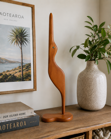 Vintage 1970s wooden bird sculpture with paua shell detail, side view on light grey studio background.