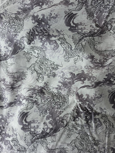 Overall view of black and grey Chinese-style dragons on white textured cotton fabric